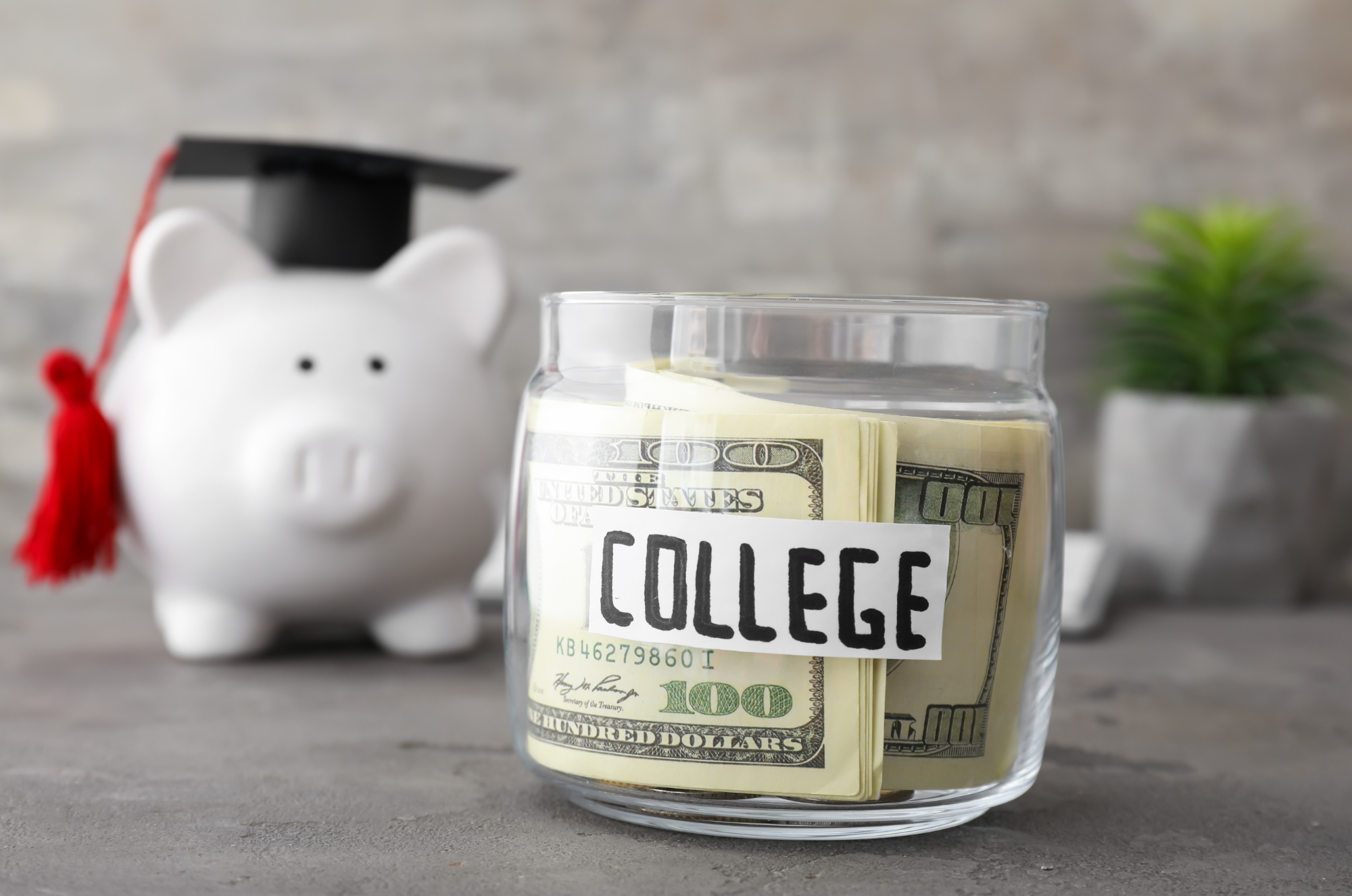 A jar of money saved for college and a piggy bank wearing a graduation cap.